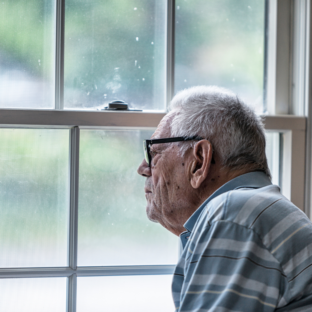 A gentleman standing looking out of a window