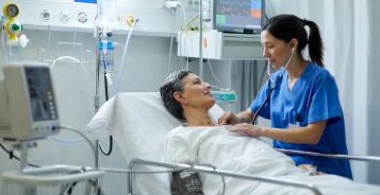 Nurse checking a patient in a hospital bed