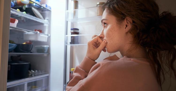 A young woman looking into her fridge