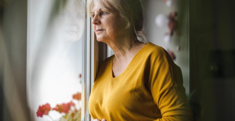 A lady standing looking out of her window