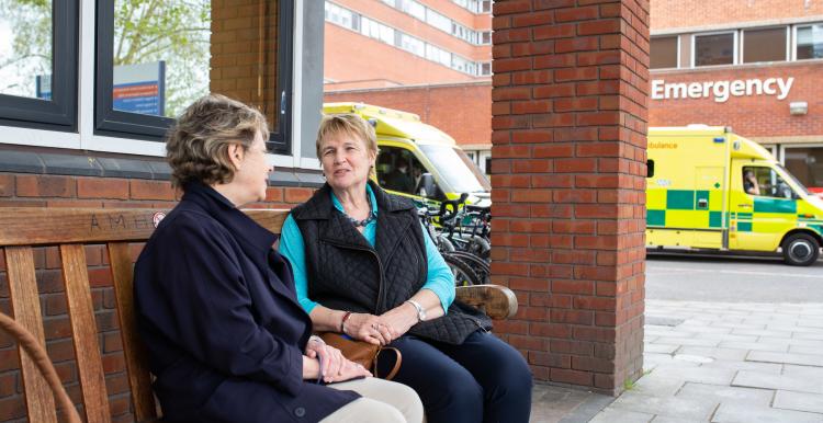 Two women sitting on a bench talking