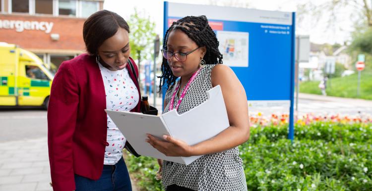 Two people looking at a folder outside a hospital