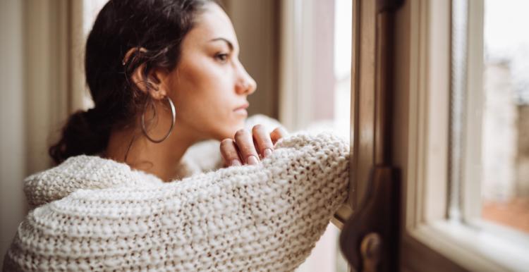 Woman looking out of window, looking pensive