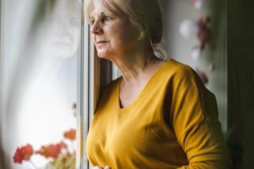 A lady standing looking out of her window