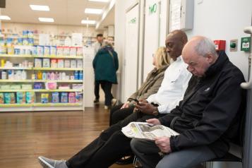 Three people waiting in a pharmacy