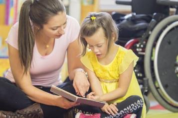 Woman with child with disability reading