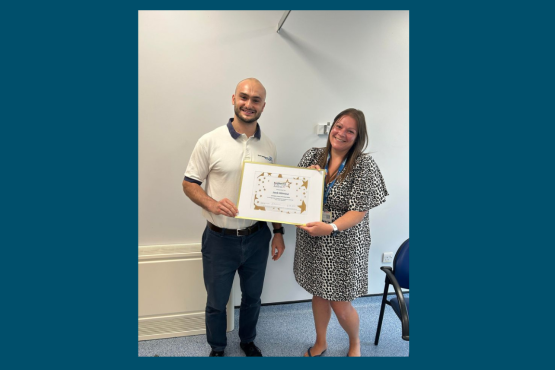 Two people standing holding a certificate and looking at the camera